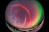 A fish-eye 360° view of a dim and weak display of Northern Lights on February 24, 2025, showing a green diffuse band to the south and a dim red curtain overhead with rays to the east. This red aurora was just visible to the eye as a grey streak. A bright meteor is at lower left below the Milky Way in the northwest. The Big Dipper is at centre almost overhead at the zenith.