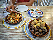 Indulging in papas arrugás with mojos and Canarian-style clams in Órzola, Lanzarote, showcasing the local flavors of the Canary Islands.
