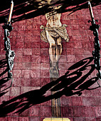 Ceramic artwork depicting Cristo del Amor on Villegas Street with shadows from nearby decorations creating an artistic interplay of light.