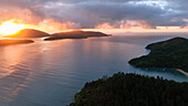 Aerial view of a tranquil sunrise over a picturesque island with a sailboat in the serene ocean, Parque Das Palmeiras, Angra dos Reis, Rio de Janeiro, Brazil.