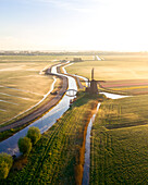Drohnenansicht einer klassischen holländischen Windmühle bei Sonnenaufgang mit Nebel, Frühling in Holland, die Niederlande