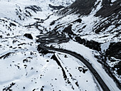 Aerial view of winding road through majestic snowy mountains, Julierpass, Grisons, Switzerland.