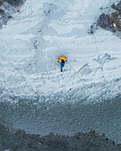 Luftaufnahme einer Frau, die an einem ruhigen, mit Schnee und Eis bedeckten Strand spazieren geht, Pentakomo, Limassol, Zypern.