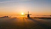 Drohnenansicht einer klassischen holländischen Windmühle bei Sonnenaufgang mit Nebel, Schermerhoorn, Frühling in Holland, Niederlande