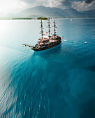 Aerial view of a beautiful ship sailing on the serene sea with majestic mountains in the background, Antalya, Turkiye.