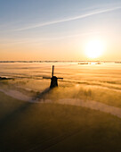 Drohnenansicht einer klassischen holländischen Windmühle bei Sonnenaufgang mit Nebel, Schermerhoorn, Frühling in Holland, Niederlande