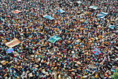 Aerial view of a bustling cattle market under colorful canopies, alive with trade and vibrant movement, a sea of people and livestock, Mahasthan, Rajshahi Division, Bangladesh.