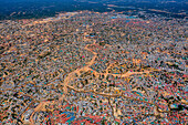 Aerial view of a sprawling settlement with tightly-packed structures and dusty pathways, creating a textured landscape under the sun, Balukhali Bazar, Chittagong Division, Bangladesh.