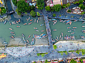 Aerial view of a river crowded with boats and people, with a bridge connecting bustling banks, creating a vibrant tapestry of color and movement, H?i An, Qu?ng Nam, Vietnam.