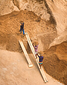 Aerial view of workers unloading sand with baskets at a work site, Darus Salam Thana, Dhaka, Bangladesh.