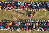 Shibganj, Bangladesh - 19 February 2022: Aerial view of a colorful communal meal during a majlis public food offering with people gathered on grass, Saidpur, Rajshahi, Bangladesh.