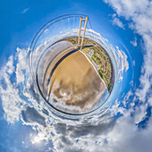 Aerial view of tiny planet perspective of the Humber Bridge over the river with beautiful clouds and blue sky, Hessle, England, United Kingdom.