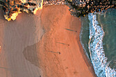 Aerial view of beautiful beach with sandy shore, cliffs, and ocean waves at sunset, Algave, Portugal.