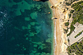 Aerial view of beautiful beach with rugged cliffs and clear sea, Algarve, Portugal.