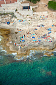 Aerial view of a picturesque beach with people sunbathing on sandy shores and rocky outcrops, Pula, Istria, Croatia.