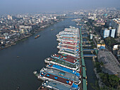 Aerial view of ships on the Buriganga River with a beautiful cityscape and modern buildings, Dhaka, Bangladesh.