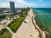 Luftaufnahme des sonnenverwöhnten Strandes, der auf den türkisfarbenen Ozean trifft, Hochhäuser, die den Horizont betonen, ein lebhafter Kontrast zwischen Natur und Architektur, Miami Beach, Florida, Vereinigte Staaten.