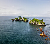 Luftaufnahme von grünen Inseln im Kontrast zum tiefblauen Meer, wo felsige Vorsprünge auf den Ozean in der Nähe der Insel Bota, Limbe, Südwestkamerun, treffen.