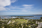Aerial view of lush green parkland contrasts with the bright blue water and boats in Biscayne Bay, a vibrant scene of nature and leisure, Miami, Florida, United States.
