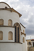 Blick auf ein strahlend weißes Gebäude mit gewölbten Fenstern unter einem bewölkten Himmel, der architektonische Details und Strukturen erkennen lässt, Pano Lefkara, Larnaca, Zypern.