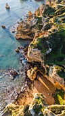 Aerial view of rugged cliffs meet the turquoise sea, with golden beaches nestled in coves, creating a stunning contrast of colors and textures, Lagos, Algarve, Portugal.