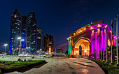 View of illuminated archway and skyscrapers pierce the twilight sky, a modern marvel blending with tradition, Abu Dhabi, Abu Dhabi, United Arab Emirates.