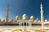 View of the Sheikh Zayed Mosque's pristine white marble gleaming under the intense blue sky in a mesmerizing display of Islamic architecture, Abu Dhabi, Abu Dhabi, United Arab Emirates.