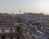 View of the ochre-toned buildings nestled together under a hazy sky, creating an intricate tapestry of urban life, Jaipur, Rajasthan, India.