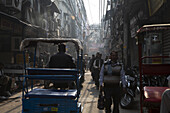 New Delhi, India - 24 June 2025: View of bustling street scene with rickshaws and pedestrians amidst the dense urban landscape, a symphony of muted tones and vibrant street life..