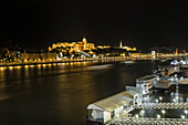 View of the Danube River reflecting the city lights, with the Buda Castle district glowing atop Castle Hill, Budapest, Central Hungary, Hungary.