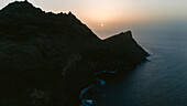 Luftaufnahme der zerklüfteten Küste, wo dunkle Klippen bei Sonnenuntergang auf den schimmernden Ozean treffen und lange Schatten auf das Wasser werfen, Mirador del Balcón, Kanarische Inseln, Spanien.
