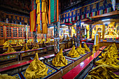 View of vibrant yellow ceremonial robes draped on benches under ornate ceilings, a rich tapestry of tradition and artistry, Ikir, Ladakh Division, India.