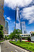 Blick auf den Wolkenkratzer One World Trade Center, der den strahlend blauen Himmel über einem üppig grünen Park durchbricht, eine Symphonie der städtischen Natur, New York, New York, Vereinigte Staaten.