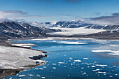 View of serene blue waters reflect the crisp, icy landscape and snow-capped mountains under a vast sky, painting a vivid picture of Arctic beauty, Svalbard, and Jan Mayen.