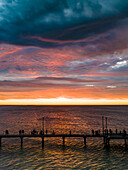 Luftaufnahme eines Piers, der sich in den Ozean erstreckt, während der Sonnenuntergang den Himmel mit leuchtenden orange- und rosafarbenen Tönen färbt, Westaustralien, Westaustralien, Australien.