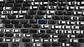 Aerial view of a sea of monochrome cars punctuated by a single vibrant blue vehicle, reflecting individuality amidst uniformity, Fremantle, Western Australia, Australia.