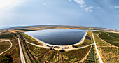 Luftaufnahme eines Stausees, in dem sich die sanften Farbtöne des Himmels spiegeln, inmitten von Feldern und Obstplantagen, eine ruhige Szene ländlicher Harmonie, Shomrat, Norddistrikt, Israel.