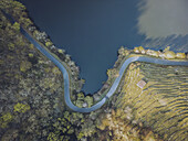 Luftaufnahme einer kurvenreichen Straße entlang des ruhigen Flusses, die im Kontrast zur üppig grünen Landschaft steht, Lugo, Lugo, Spanien.
