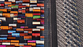 Long Beach, United States - 07 April 2025: Aerial view of a multitude of shipping containers creating a vibrant tapestry of colors against the stark, geometric lines of the port's infrastructure.