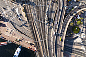 Aerial view of intertwining railway tracks, roads, and watercraft create a tapestry of urban motion and stillness near the waterfront, Stockholm, Stockholm County, Sweden.