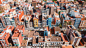 Luftaufnahme von dicht gedrängten Gebäuden mit einem Mosaik aus roten Ziegeldächern und lebendigen Fassaden, die einen dichten städtischen Wandteppich bilden, Valencia, Valencianische Gemeinschaft, Spanien.
