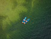 Luftaufnahme von zwei Personen, die auf dem Galve-See paddeln. Das grüne Wasser spiegelt den Himmel und schafft eine ruhige und malerische Szene, Trakai, Vilnius Land, Litauen.