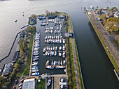 Aerial view of boats docked neatly in lines along the marina's edge, reflecting the sky in their polished surfaces, Amsterdam, North Holland, Netherlands.