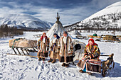 Yamalo Nenets, Russia - 16 April 2021: View of indigenous women standing proudly near their traditional dwellings against a backdrop of stark white snow-covered mountains.