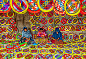 Gaibandha, Bangladesh - 04 September 2020: View of women crafting colorful fans in a vibrant display of traditional artistry, the patterns a kaleidoscope of geometric shapes against a simple backdrop.