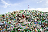Chittagong, Bangladesh - 22 September 2022: View of a young boy amidst a mountain of discarded plastic bottles under a vast, open sky, a stark contrast of human presence and environmental challenge.