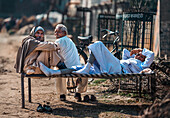 Kolkata, India - 28 January 2023: View of three men, one reclining, on a charpai, their weathered faces telling stories of life under the warm Indian sun.