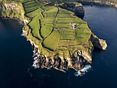 Luftaufnahme von smaragdgrünen Feldern, die auf den saphirblauen Ozean treffen, ein Küstenteppich der Kunstfertigkeit der Natur, Vila Franca do Campo, Azoren, Portugal.
