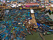 Aerial view of a bustling harbor filled with colorful boats clustered around a pier in the city, contrasting with the market's vibrant activity, Port Harcourt, Rivers State, Nigeria.