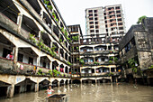 Chattogram, Bangladesh - 05 August 2023: View of a waterlogged courtyard with a child standing in the foreground, surrounded by aged buildings and a taller, unfinished structure.